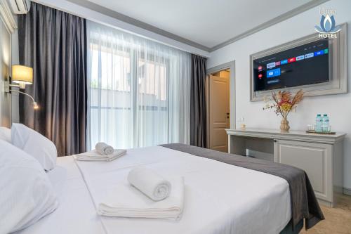 a hotel room with a white bed and a television at Daria Boutique Hotel in Eforie Sud