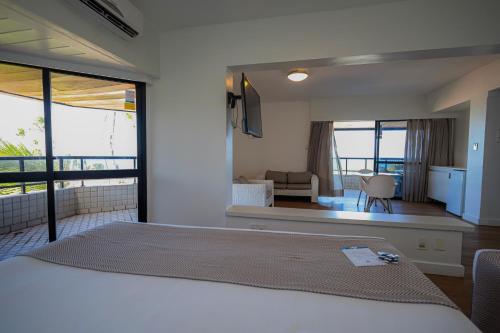 a bedroom with a bed and a view of a living room at Maceió Atlantic Suites in Maceió