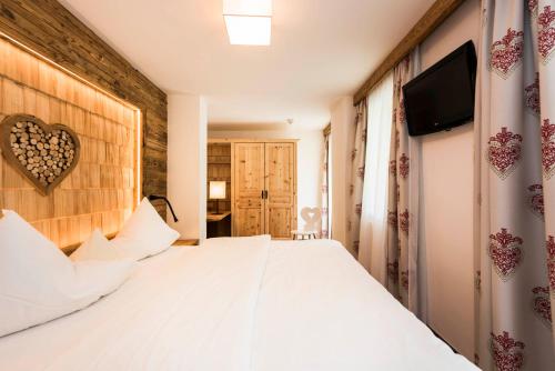 a bedroom with a white bed and a flat screen tv at Hotel Stubaierhof in Neustift im Stubaital
