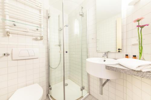 a bathroom with a shower, sink, and toilet at Novum Akademiehotel Kiel in Kiel