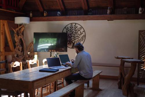 a man sitting at a table using a laptop computer at Au Bois Dormant gîte 15 personnes in Lapoutroie
