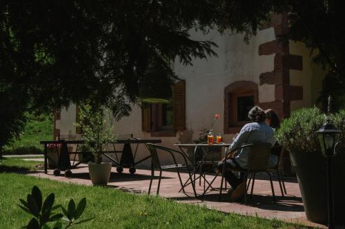 a woman sitting at a table in a yard at Au Bois Dormant gîte 15 personnes in Lapoutroie