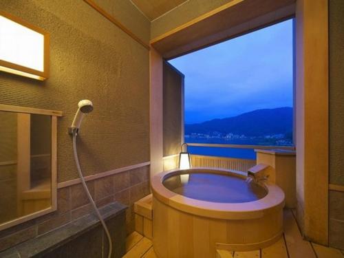 a bathroom with a bath tub with a large window at Kasuitei Ooya in Fujikawaguchiko