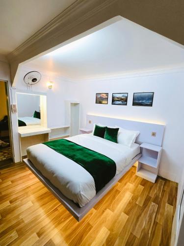 a bedroom with a large white bed with green sheets at Big Tree Hostel in Kathmandu