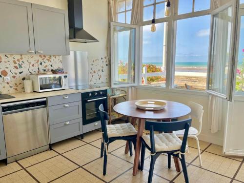 une cuisine avec une table et des chaises et une cuisine avec l'océan dans l'établissement La parenthèse marine, vue mer avec terrasse, à Arromanches-les-Bains