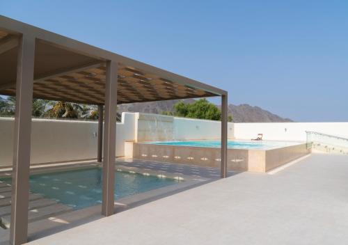 a swimming pool with a pavilion next to the beach at Ivory House Resort - Ophiolite in Hatta