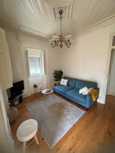 a living room with a blue couch and a chandelier at Quintinha Vale dos Pinheiros in Leiria