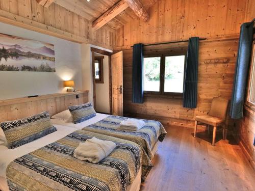 une chambre avec deux lits dans une cabane en rondins dans l'établissement Luxueux 6 pièces avec sauna, hammam et jacuzzi, à 300m du centre et au pied des télécabines! - FR-1-458-95, au Grand-Bornand