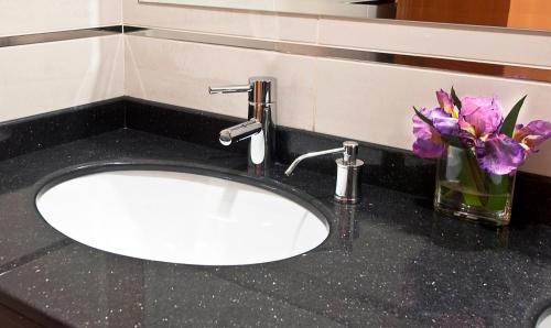 a sink in a bathroom with purple flowers in a vase at Tugcu Hotel Select in Bursa