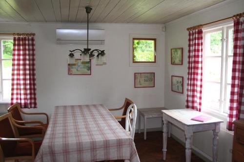 a dining room with a table and a table and two windows at Kylås Vildmark in Skillingaryd