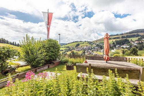 a garden with an orange umbrella and flowers at Ferienwohnungen Kehrwieder in Todtnauberg