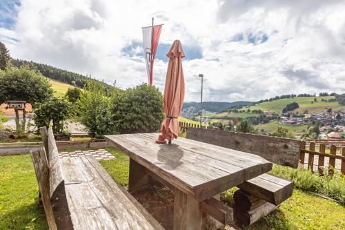 a wooden bench with an umbrella on top of it at Ferienwohnungen Kehrwieder in Todtnauberg