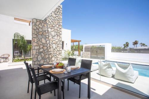 a dining room with a table and chairs and a pool at Nostos Luxury Apartments in Kremasti