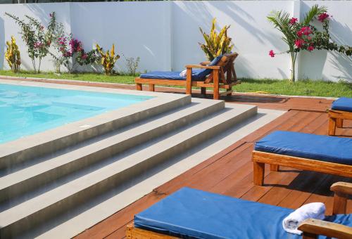 a swimming pool with two chairs and a table at MG Villa, Zanzibar in Mfumbwi
