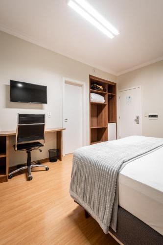 a bedroom with a bed and a desk and a computer at Hotel Kindermann in Caçador