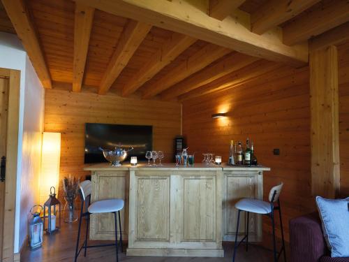 a bar in a wooden room with stools and a tv at Chalet LE VAL NESS in La Côte dʼArbroz