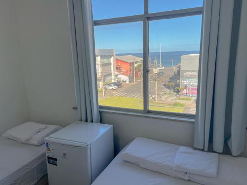 Cette chambre comprend deux lits et une fenêtre avec vue. dans l'établissement Quarto individual na Pituba 1, à Salvador
