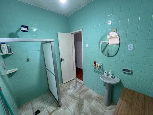 une salle de bain bleue avec un lavabo et un miroir dans l'établissement Quarto individual na Pituba 1, à Salvador