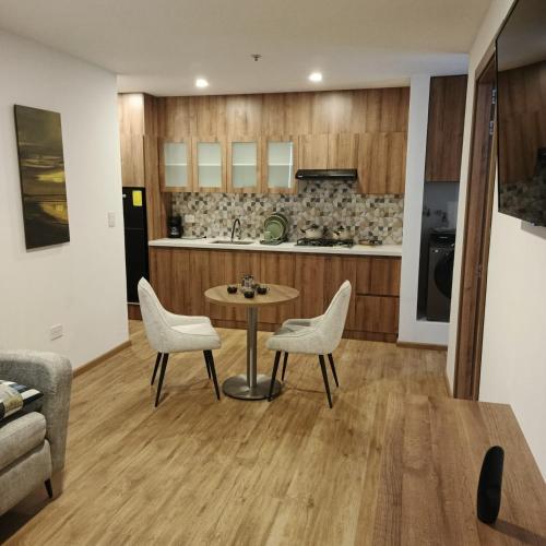 a kitchen and living room with a table and chairs at Hotel Santiago de Compostella Suites in Cuenca