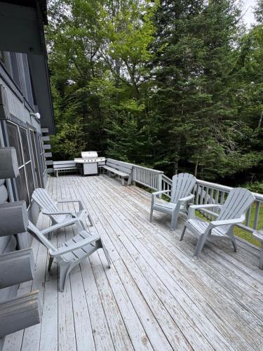 a deck with two chairs and benches on a house at Outta Range Outta Range, A Cozy Log Home Retreat in Rangeley