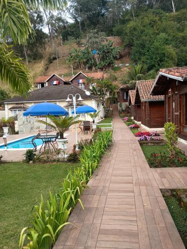 a walkway leading to a resort with a pool and umbrellas at Pousada Mon Desir in Penedo