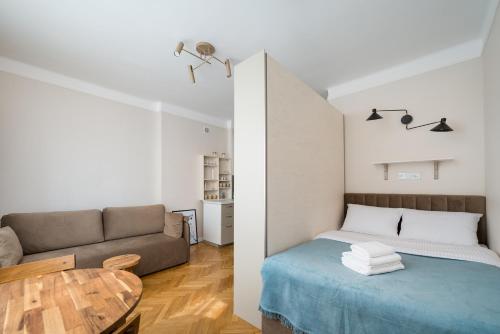 a room with a bed and a couch and a table at Widok Warsaw City Apartment by BookingHost in Warsaw