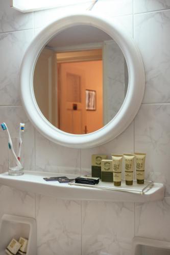 a bathroom with a mirror and a shelf with toothbrushes at Ignatia Hotel in Nafplio
