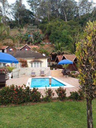 a swimming pool with blue umbrellas in a yard at Pousada Mon Desir in Penedo