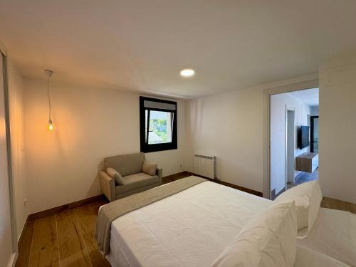 a bedroom with a bed and a chair and a window at Cíes Suitel Prado in Nigrán