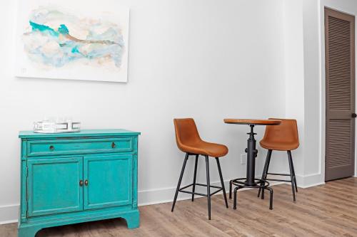a table and two stools next to a blue cabinet at Highball Heaven by Pristine Properties Vacation Rentals in Port Saint Joe