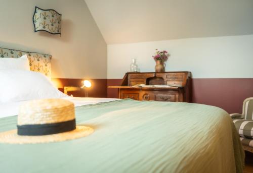 a hat is sitting on top of a bed at Le Domaine de Richebourg - Pierres d'Histoire in Richebourg
