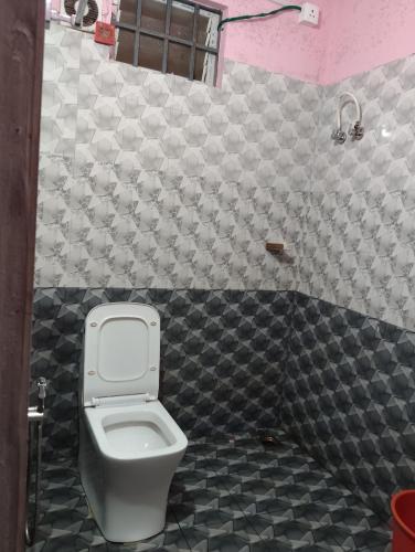 a bathroom with a toilet and a black and white tiles at Roamwander doublerooms in Vagamon