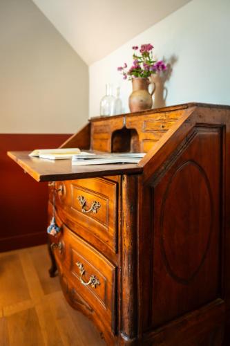 a wooden dresser with flowers on top of it at Le Domaine de Richebourg - Pierres d'Histoire in Richebourg