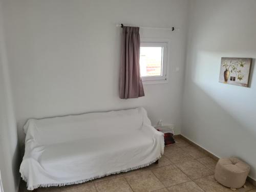 a white bed in a room with a window at Sea View House in Porto Rafti