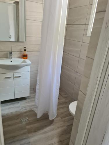 a bathroom with a sink and a white shower curtain at Sea View House in Porto Rafti