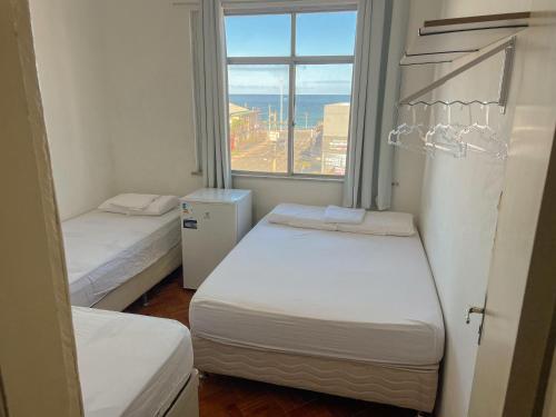zwei Betten in einem kleinen Zimmer mit Fenster in der Unterkunft Quarto individual na Pituba 1 in Salvador
