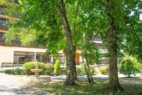 a building with trees and a fountain in front of it at Garden & City Capvern-les-Bains in Capvern