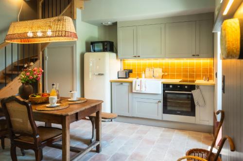 a kitchen with a wooden table and a white refrigerator at Le Domaine de Richebourg - Pierres d'Histoire in Richebourg