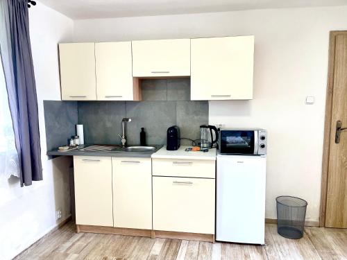 a white kitchen with white cabinets and a microwave at U Parku, Nová Ves in Křemže