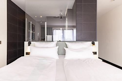 a bedroom with two beds with white pillows at Garner Hotel Oberhausen in Oberhausen
