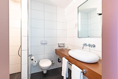 a white bathroom with a sink and a toilet at Garner Hotel Oberhausen in Oberhausen