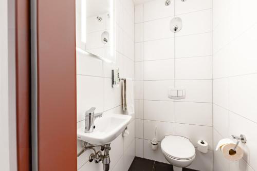 a white bathroom with a toilet and a sink at Garner Hotel Oberhausen in Oberhausen