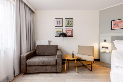 a living room with a chair and a table at Garner Hotel Oberhausen in Oberhausen