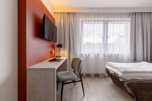 a bedroom with a bed and a desk with a television at Garner Hotel Oberhausen in Oberhausen