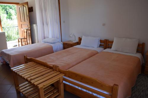 two beds in a room with a bench and a window at Hostel Gerakina ΙΙ in Vávdhos