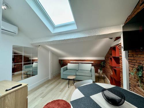 a living room with a blue couch and a brick wall at Studio place du Capitole climatisation in Toulouse