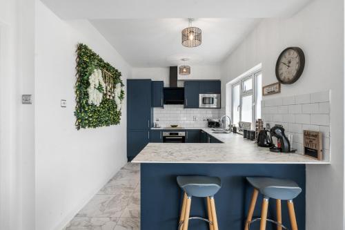 a kitchen with blue cabinets and a clock on the wall at Clarence Square 2 Bedroom Central in Brighton & Hove
