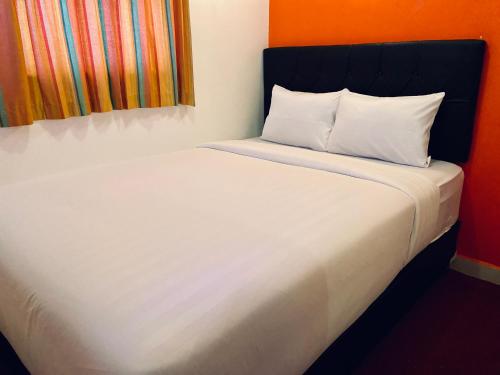 a white bed with a black headboard and white pillows at NiHOTEL Cibaduyut Bandung in Bandung