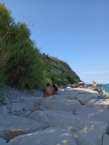 a group of people sitting on the rocks on the beach at Dimora FinAmore 29 - Casa Vacanze in Lanciano