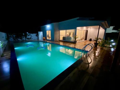 a large swimming pool at night with a house at GoBravo 71- 2BHK Farm with Pool & Garden Sector 150 Noida in Greater Noida